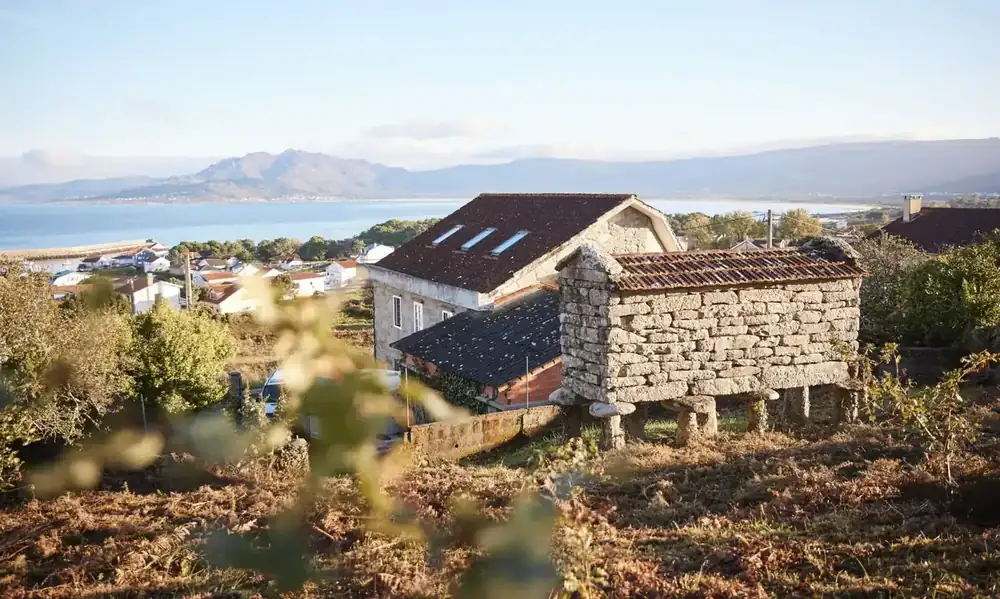Casa Mestra stone house and traditional Galician hórreo overlooking Carnota bay